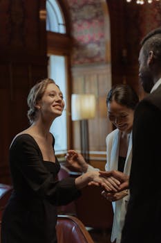 Three executives in a formal setting shaking hands and smiling, conveying professionalism and warmth.