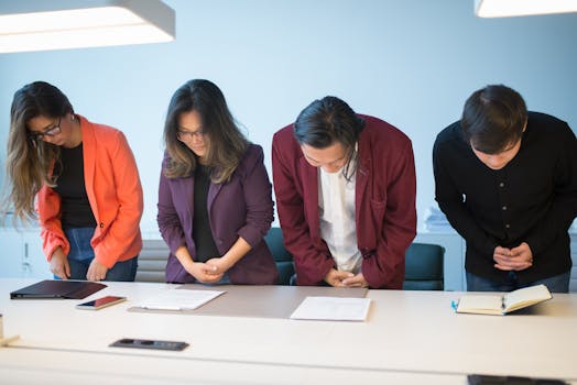 Business meeting with a diverse team bowing in respect, symbolizing cultural cooperation.