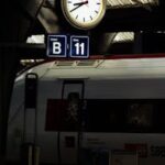 Nighttime view of Zürich railway station platform, featuring a clock and SBB train with seating information.