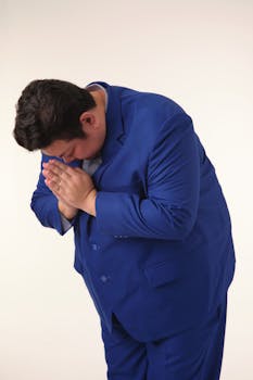 Person dressed in a vibrant blue suit performs a traditional bow with hands clasped, showing respect.