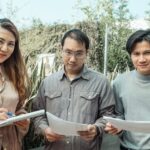 Three colleagues discussing work documents in an outdoor setting, fostering teamwork.